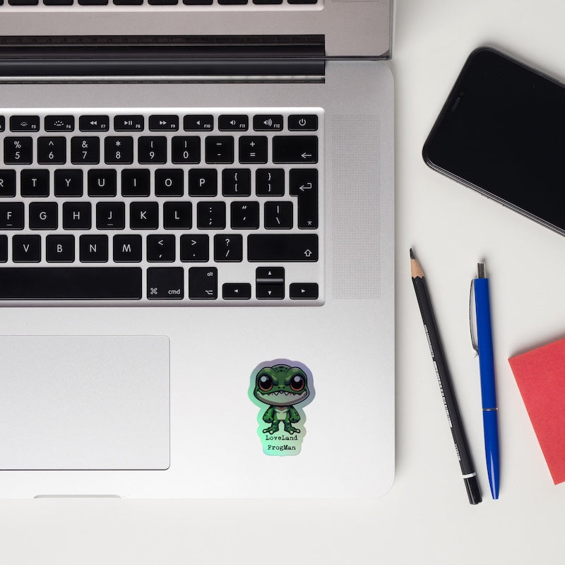 Laptop with a sticker, pencils, and a phone on a white surface
