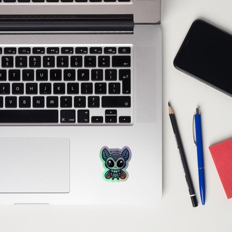 Laptop with a sticker, phone, and pens on a white surface