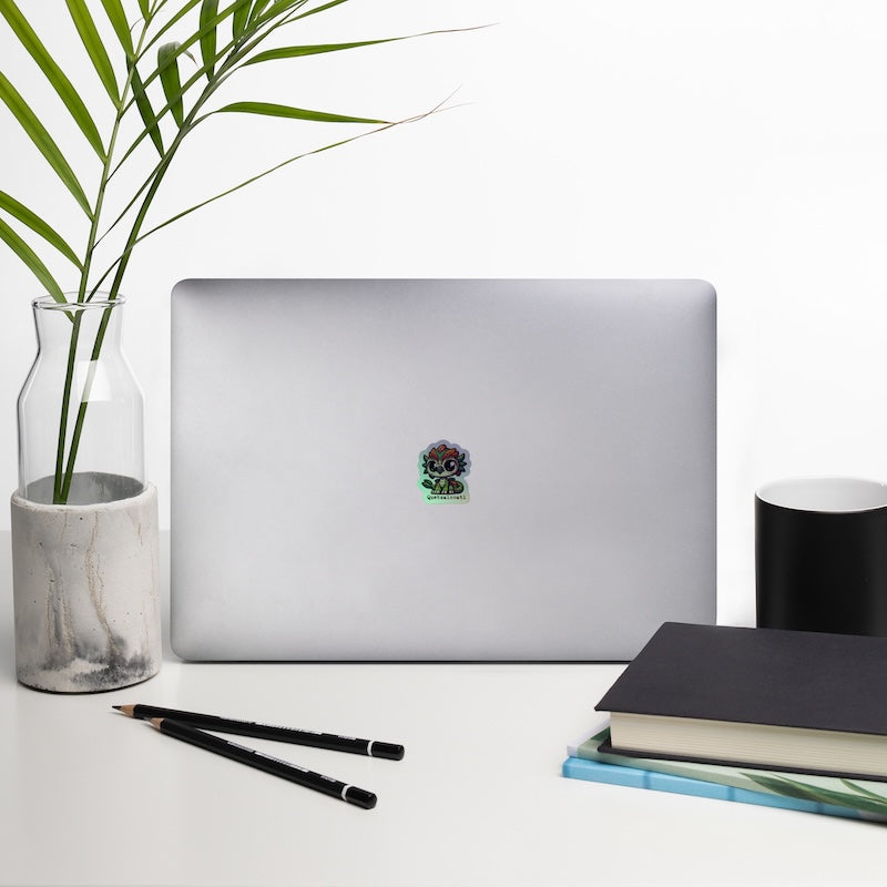 Laptop with a plant, notebook, and pencils on a white surface