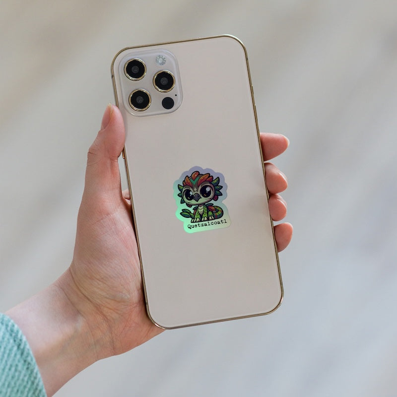 Hand holding a phone with a colorful sticker on the back against a neutral background