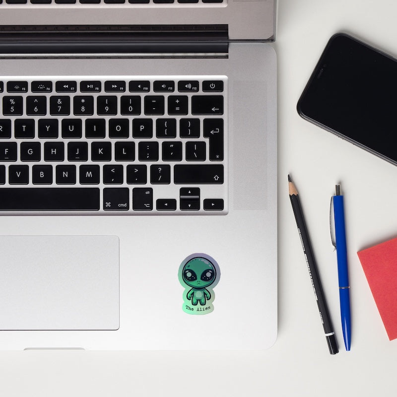 Laptop with a sticker, phone, and pens on a white surface