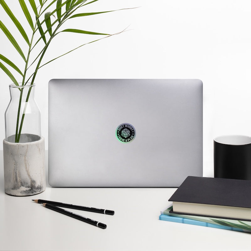 Laptop with a plant, notebook, and pencils on a white surface