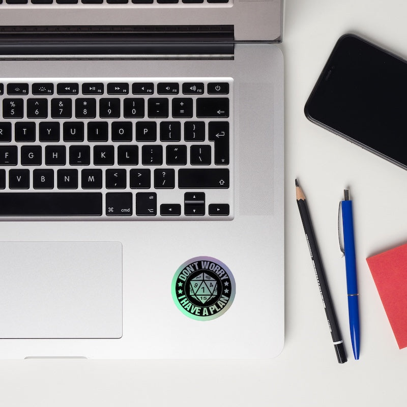 Laptop with a sticker, phone, and writing utensils on a white surface
