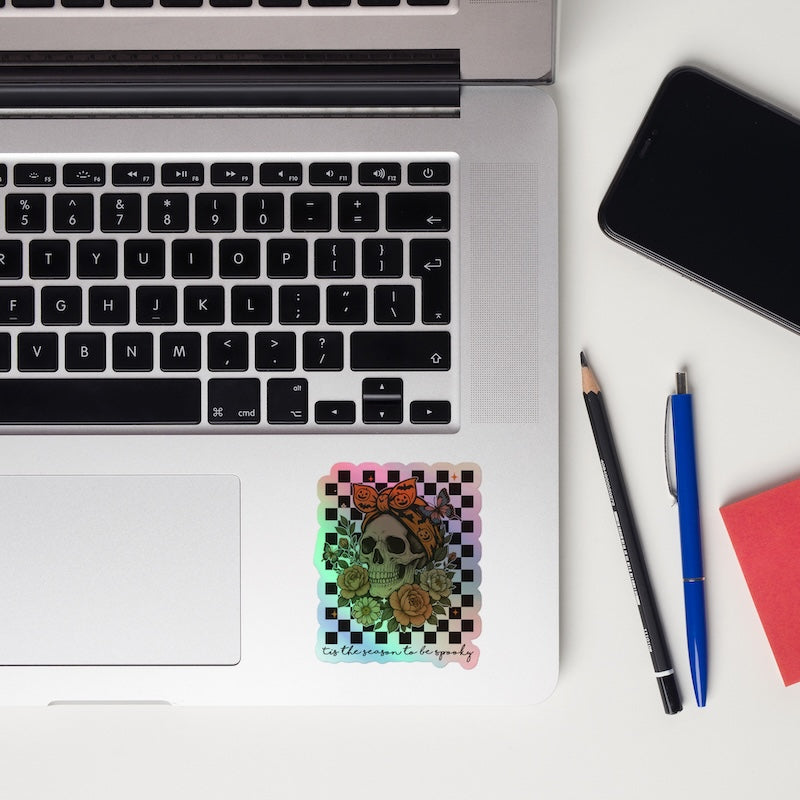 Laptop with a colorful card, pencils, and a phone on a white surface