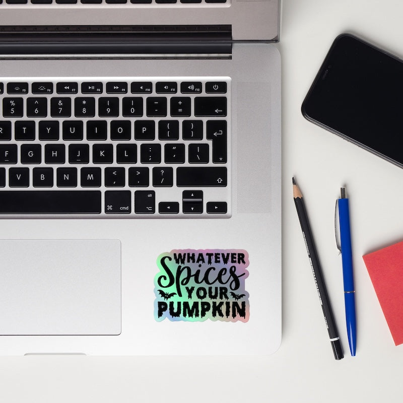Laptop with a colorful sticker on a white surface, next to a phone, pencil, and pen.