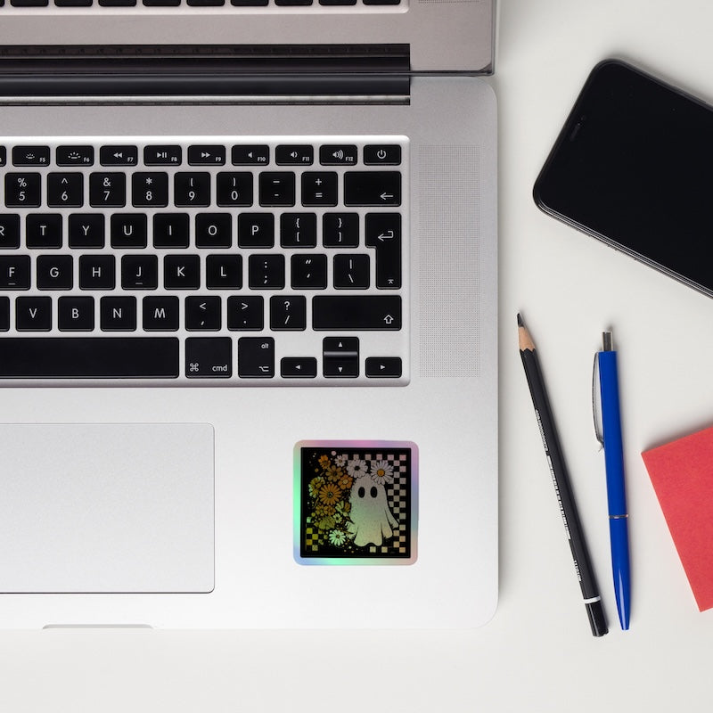 Laptop with a sticker, phone, pencil, pen, and notebook on a white surface