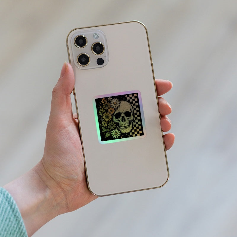 Hand holding a phone with a colorful skull design on the back