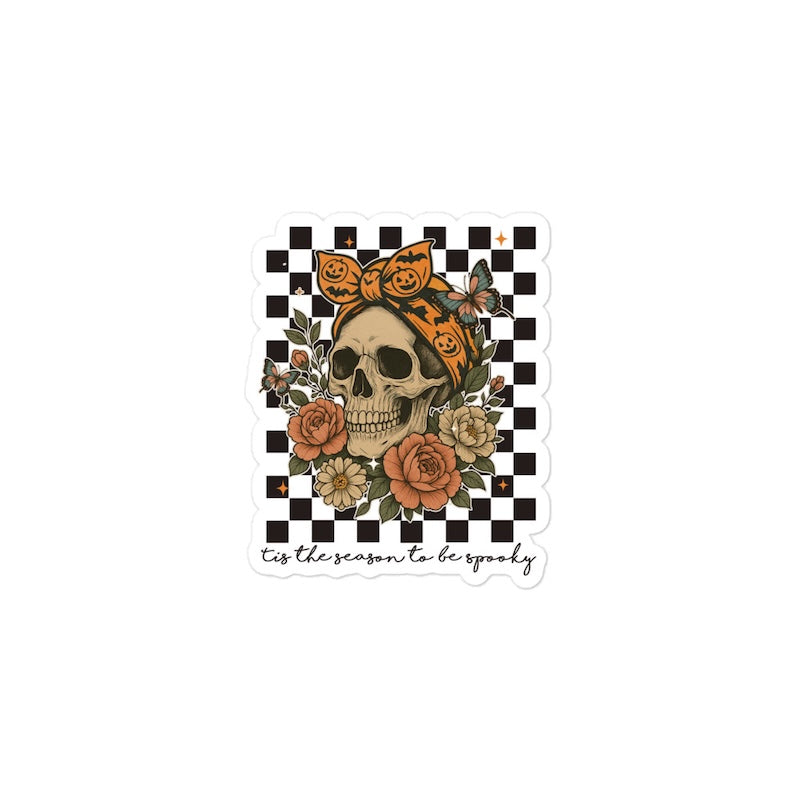 Sticker with a skull, flowers, and pumpkins on a checkered background with text.
