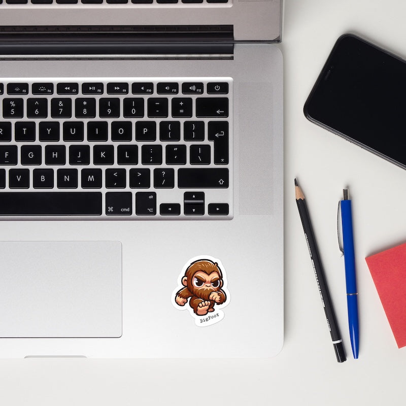 Laptop with a sticker, phone, and stationery items on a white surface