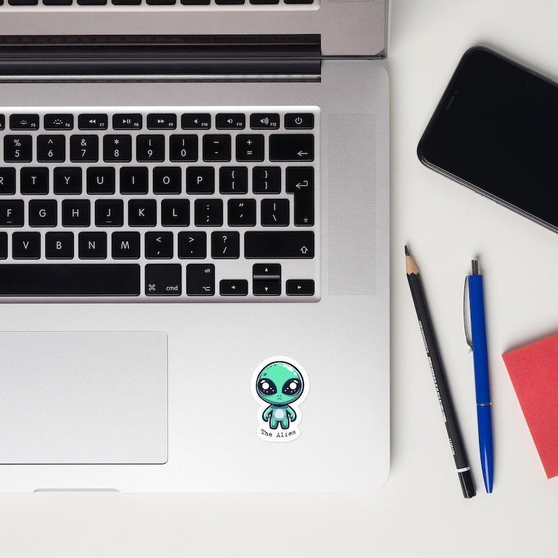 Laptop with a sticker, smartphone, and stationery items on a white surface