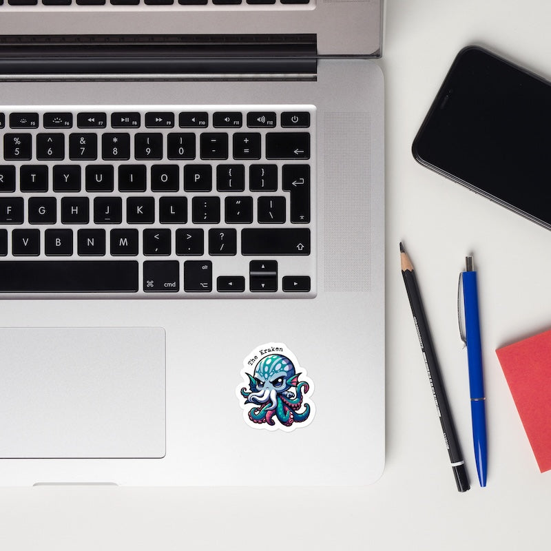 Laptop with a sticker, phone, pencils, and notebook on a white surface