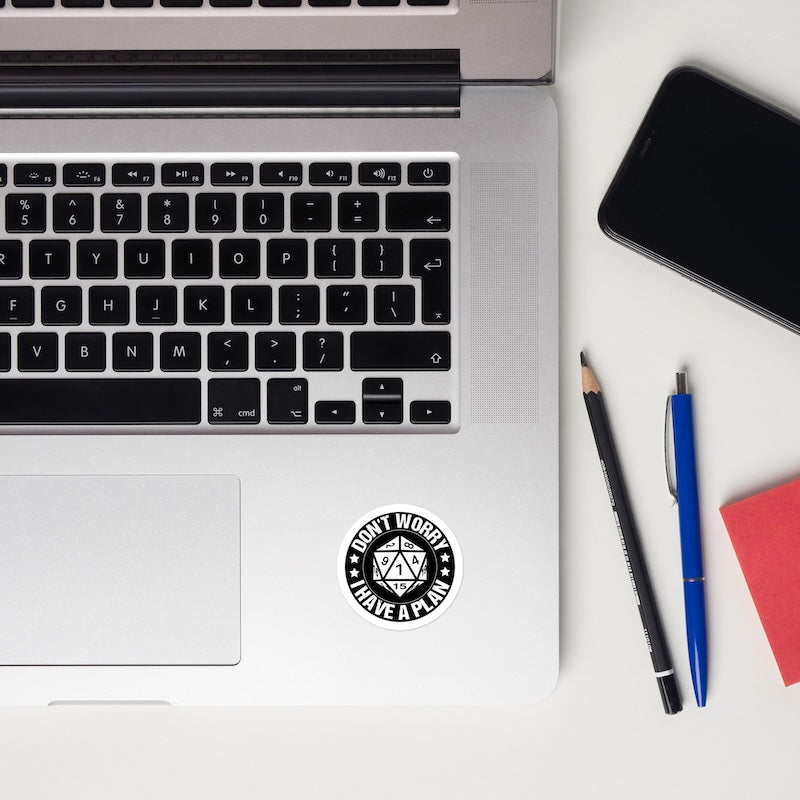 Laptop with a sticker, pencils, and a phone on a white surface