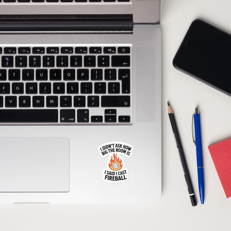 Laptop with a sticker, smartphone, and pens on a white surface