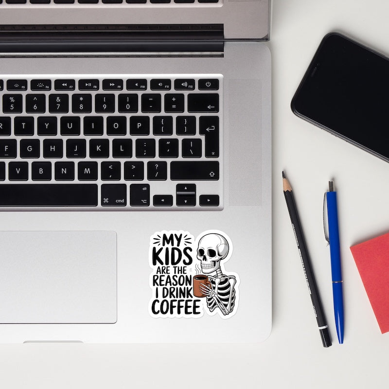 Laptop with a skeleton sticker and stationery items on a white surface