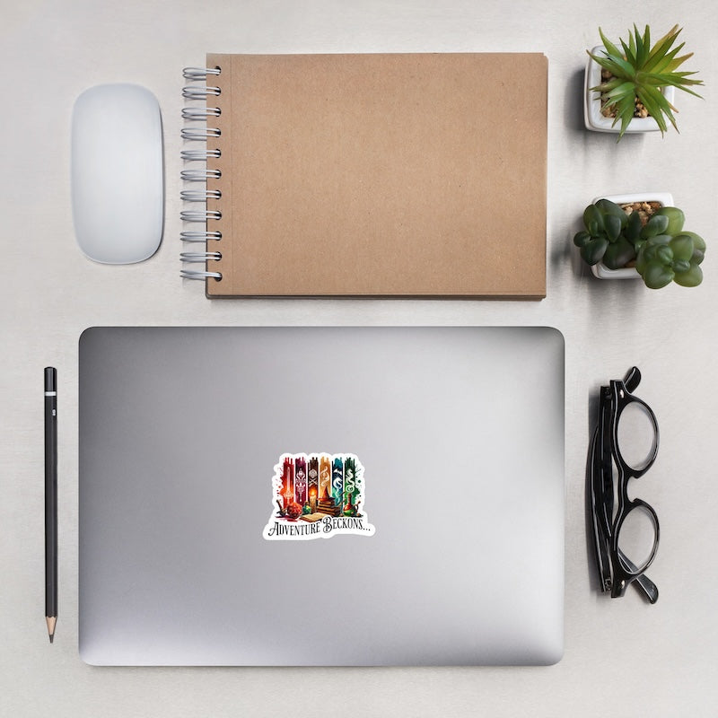 Laptop with 'Adventure Awaits' sticker, notebook, mouse, pencil, glasses, and plants on a light surface