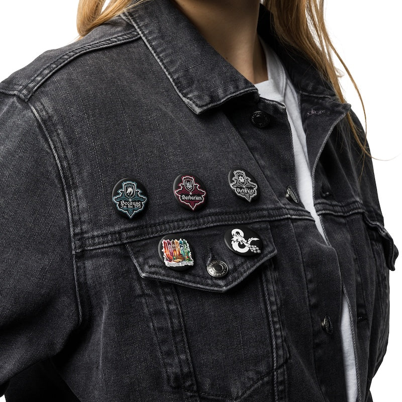 Black denim jacket with various pins on a white background