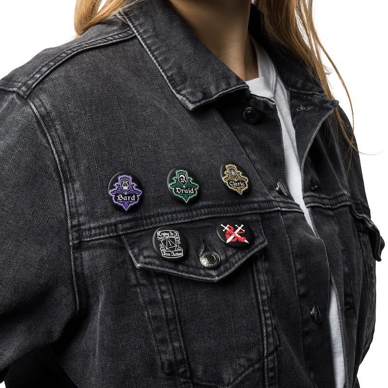 Black denim jacket with various pins on a white background