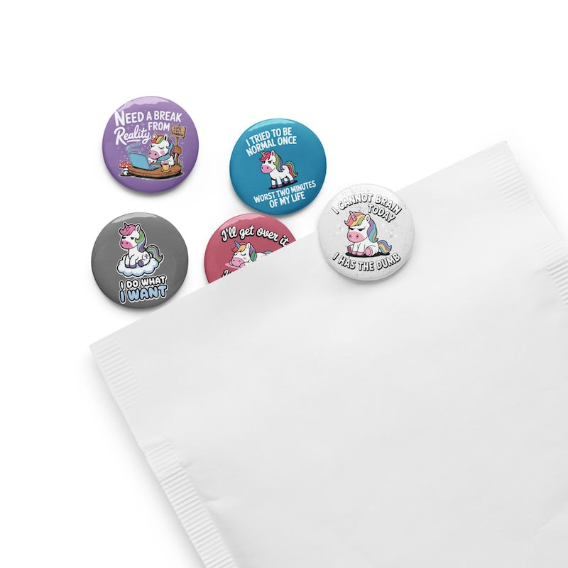 Set of five colorful buttons with unicorn designs and humorous text on a white surface.
