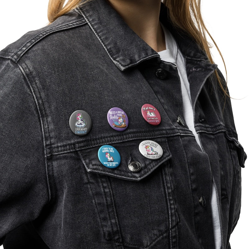 Person wearing a black denim jacket with various buttons on a white background
