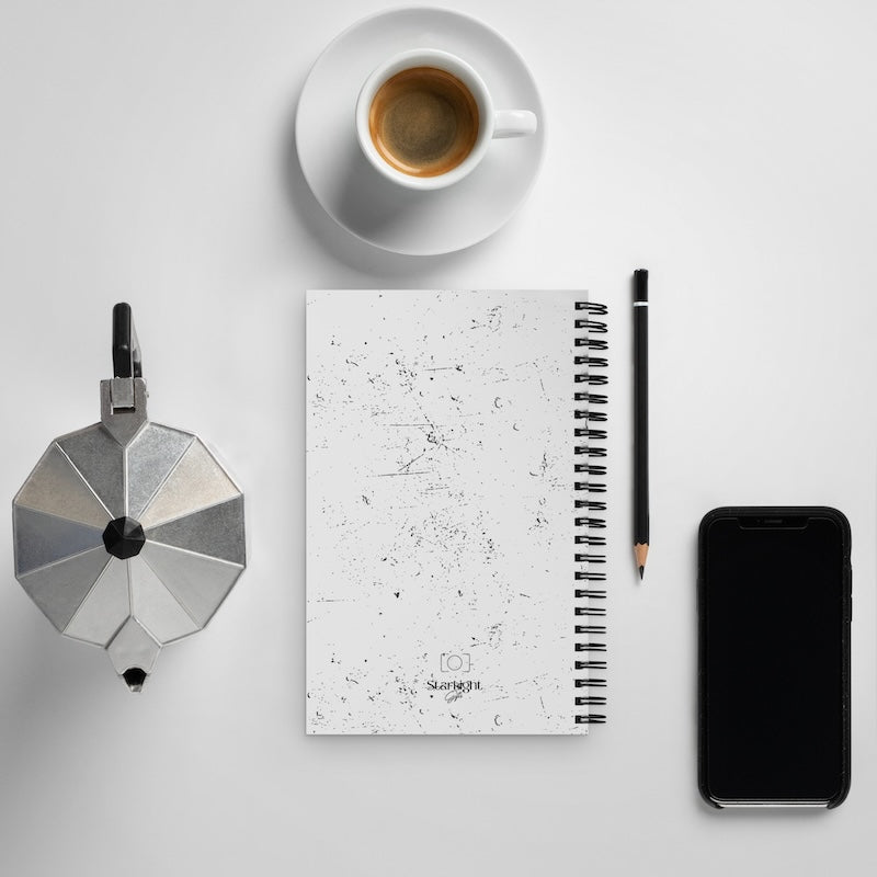 Notebook with a coffee cup, pencil, and smartphone on a light gray background