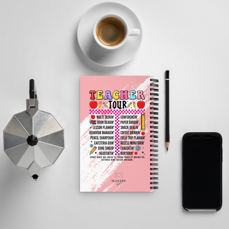 Notebook titled 'Teacher Tour' with a cup of coffee, phone, and stationery on a light gray background