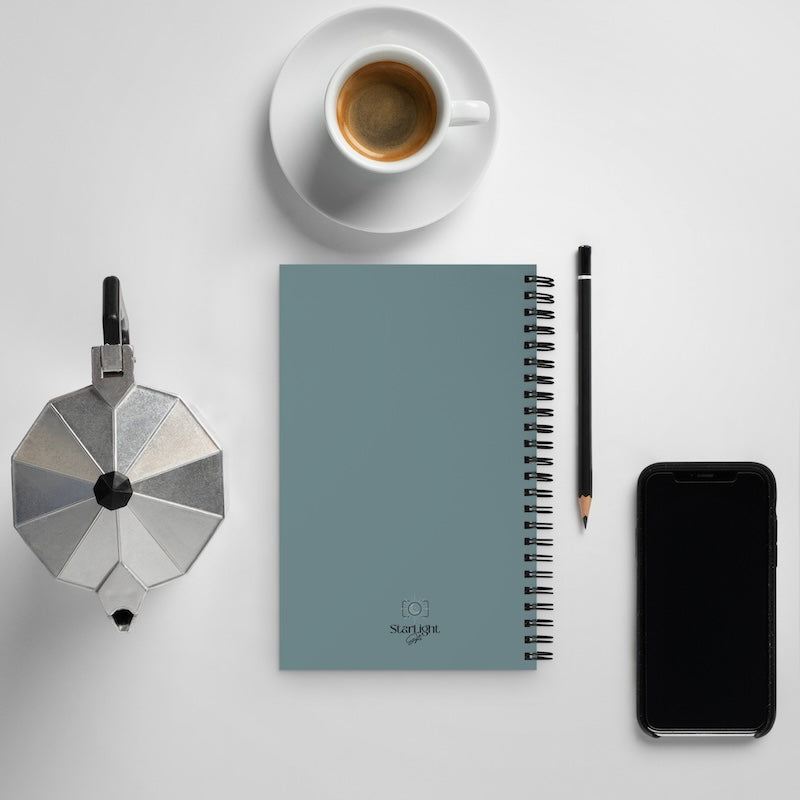 Notebook with a pen, smartphone, and coffee cup on a light gray background
