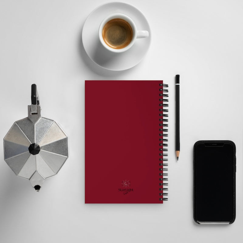 Red notebook with a coffee cup, pencil, and smartphone on a white surface