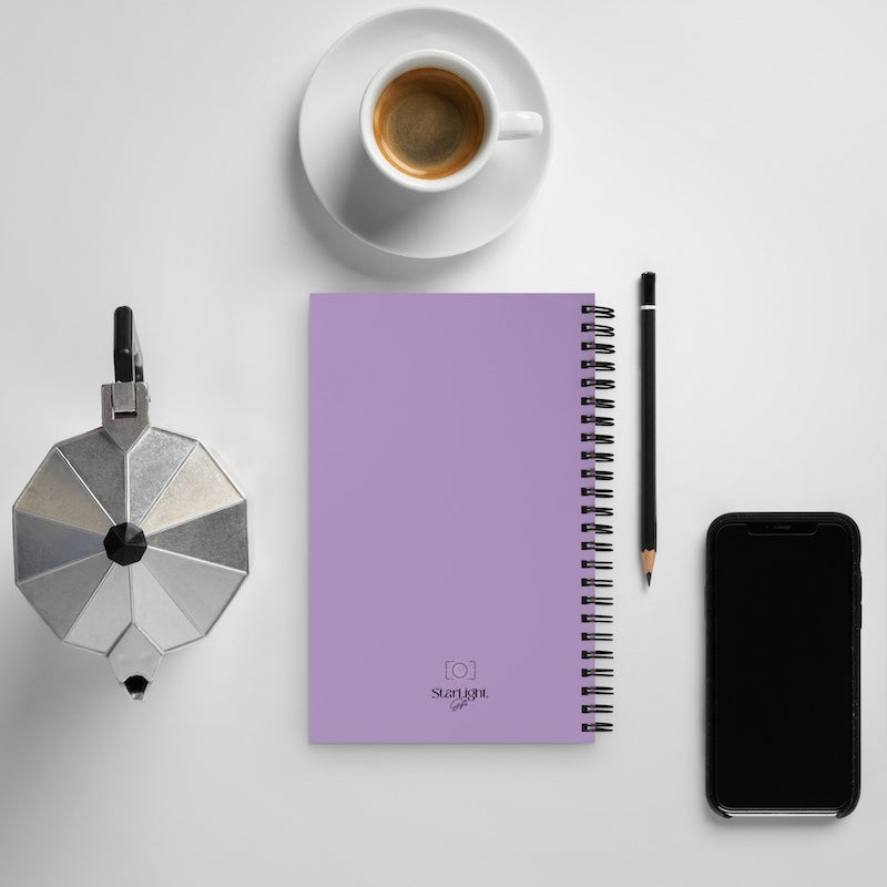 Purple notebook with a pen, smartphone, and coffee cup on a light gray background
