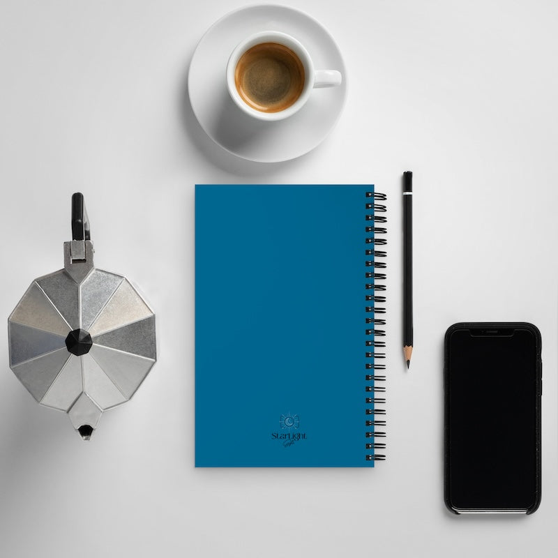 Blue notebook with a coffee cup, pencil, and smartphone on a white surface