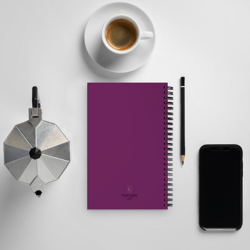 Purple notebook with a coffee cup, pencil, and phone on a white surface