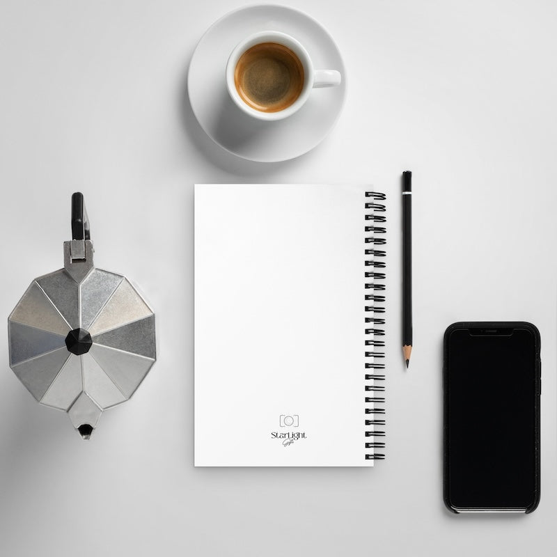 Flat lay of a coffee maker, notebook, pencil, and smartphone on a light gray surface.