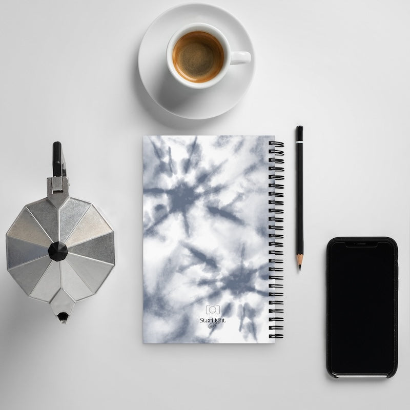 Notebook with a tree pattern, coffee cup, phone, and other items on a light gray background