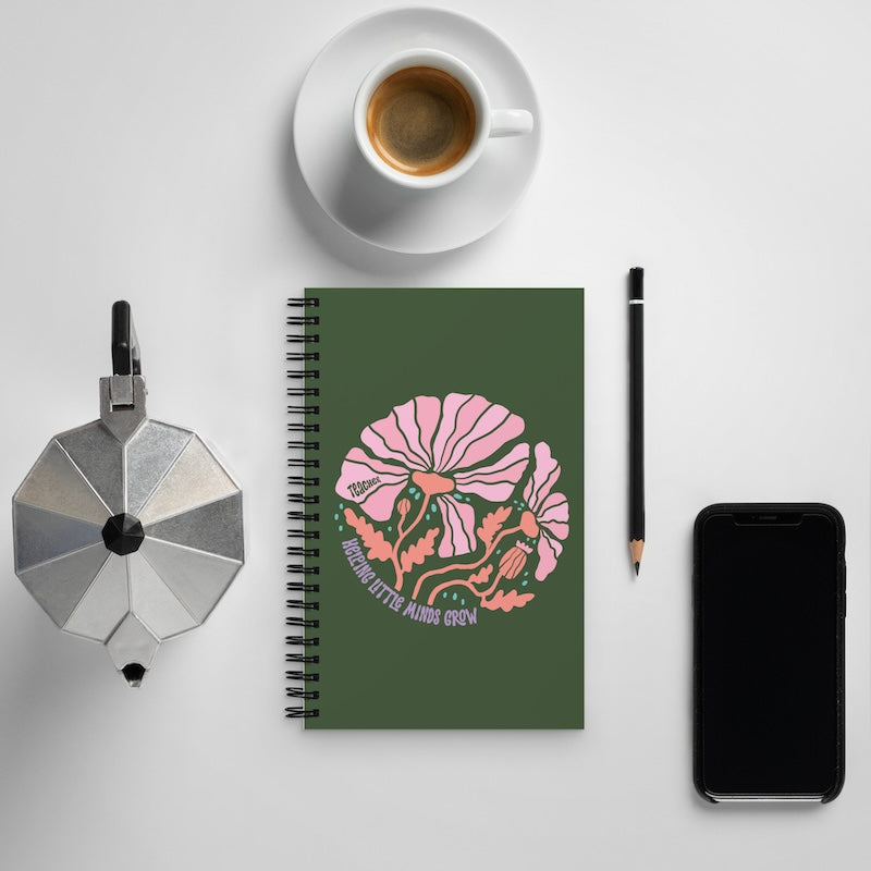 Notebook with floral design, coffee cup, phone, and pencil on a light gray background