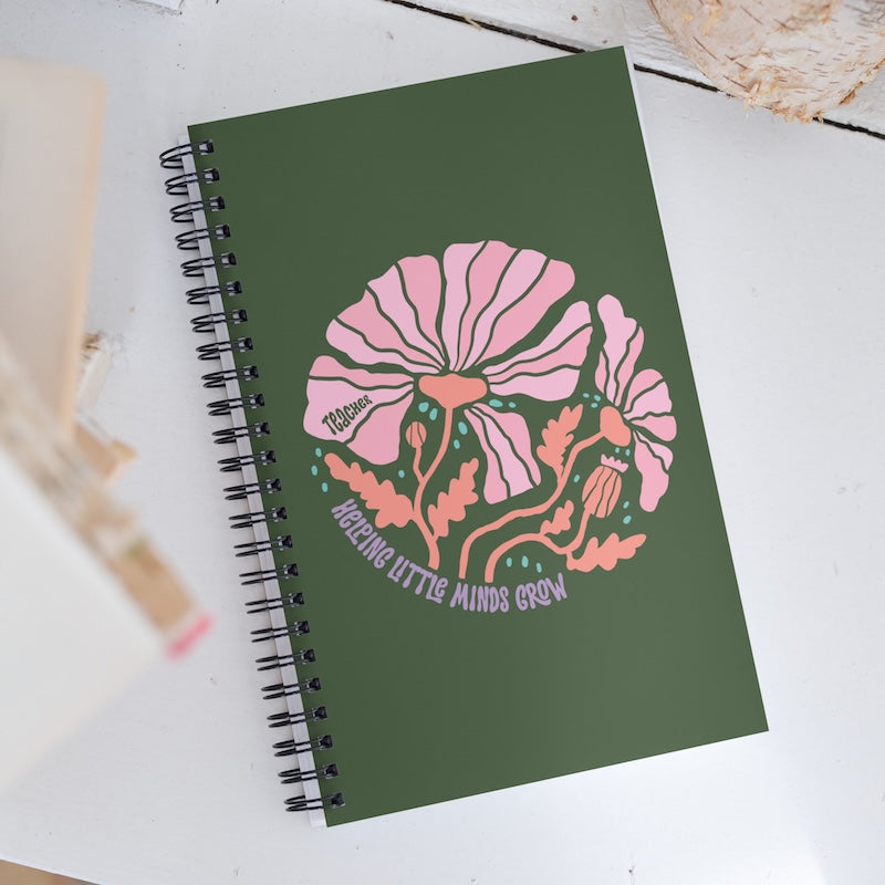 Green notebook with pink floral design and text on a white surface
