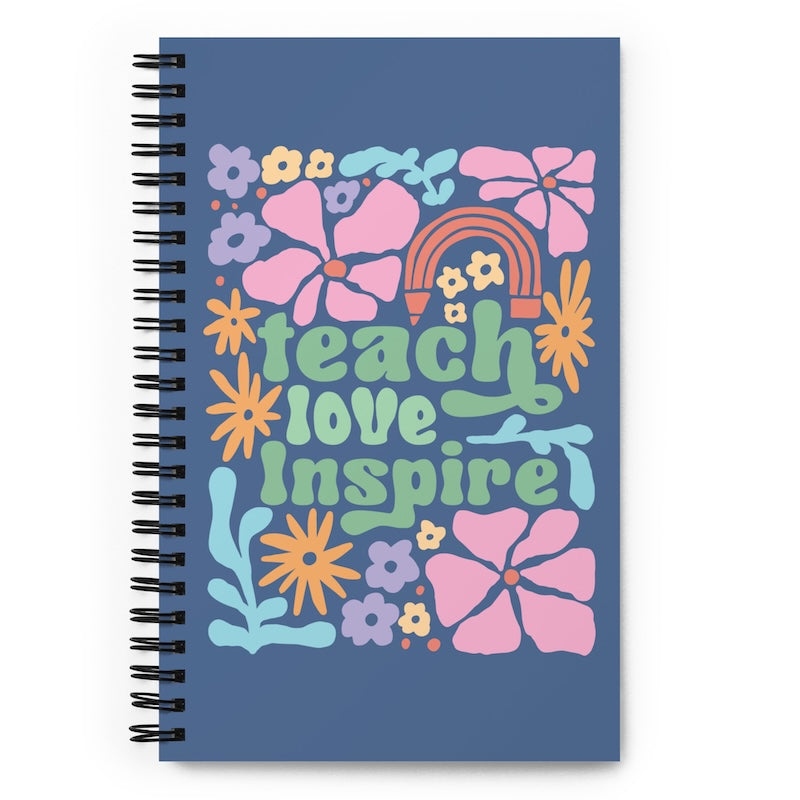 Notebook with colorful floral design and 'teach love inspire' text on a blue background
