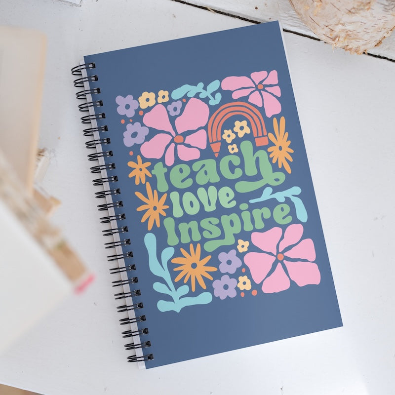 Notebook with colorful design and text 'Teach Love Inspire' on a white surface