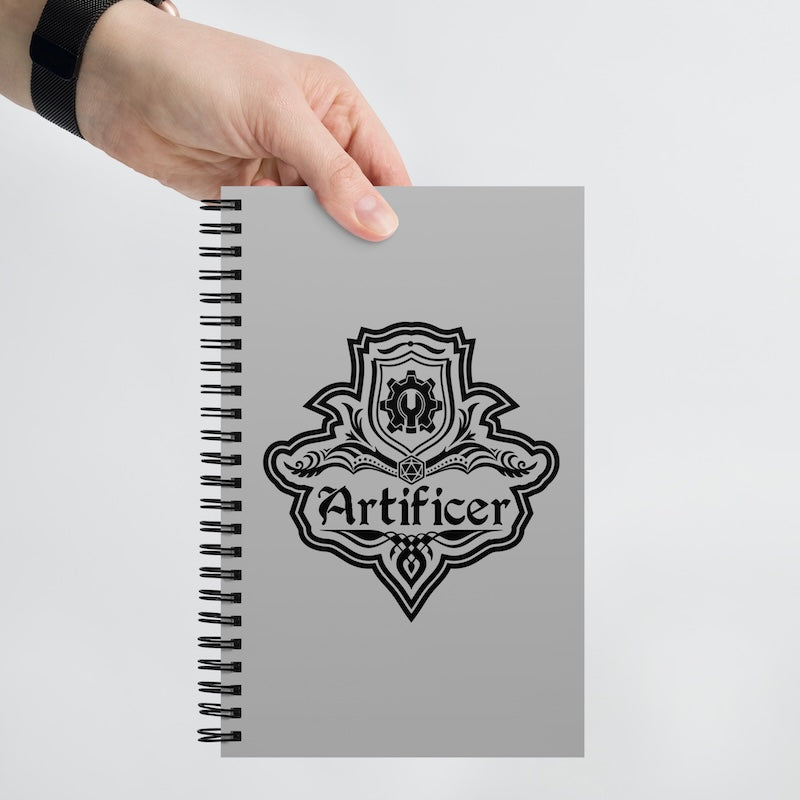 Notebook with 'Artificer' design held by a hand on a light gray background