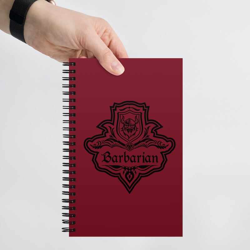 Red notebook with 'Barbarian' design held by a hand on a light gray background