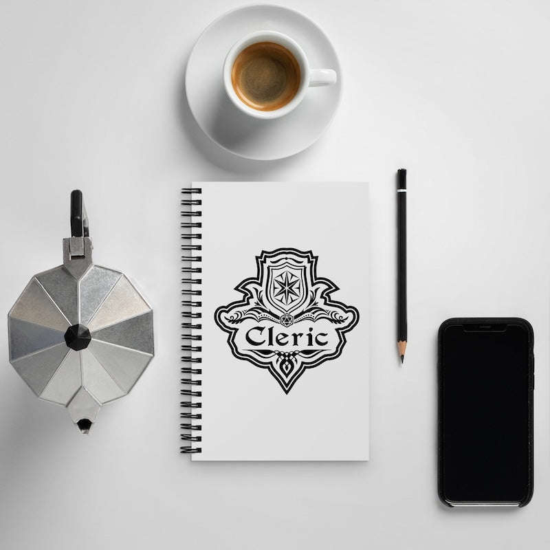Notebook with 'Cleric' design, coffee cup, phone, and pen on a white surface