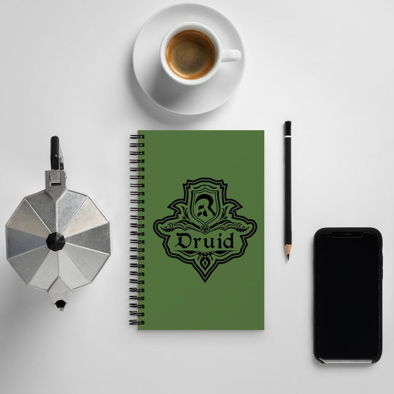 Green notebook with 'Druid' design, coffee cup, pencil, and phone on a white surface