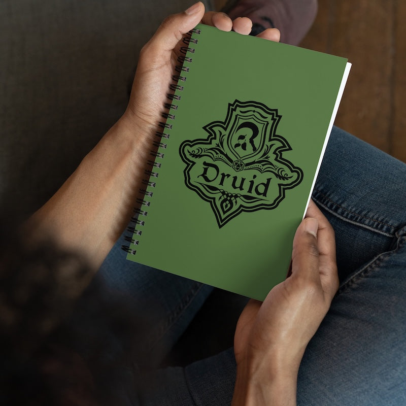 Green notebook with 'Druid' design held by a person wearing jeans.