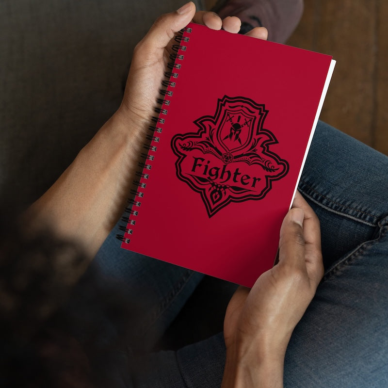 Red notebook with 'Fighter' design held by a person wearing jeans.