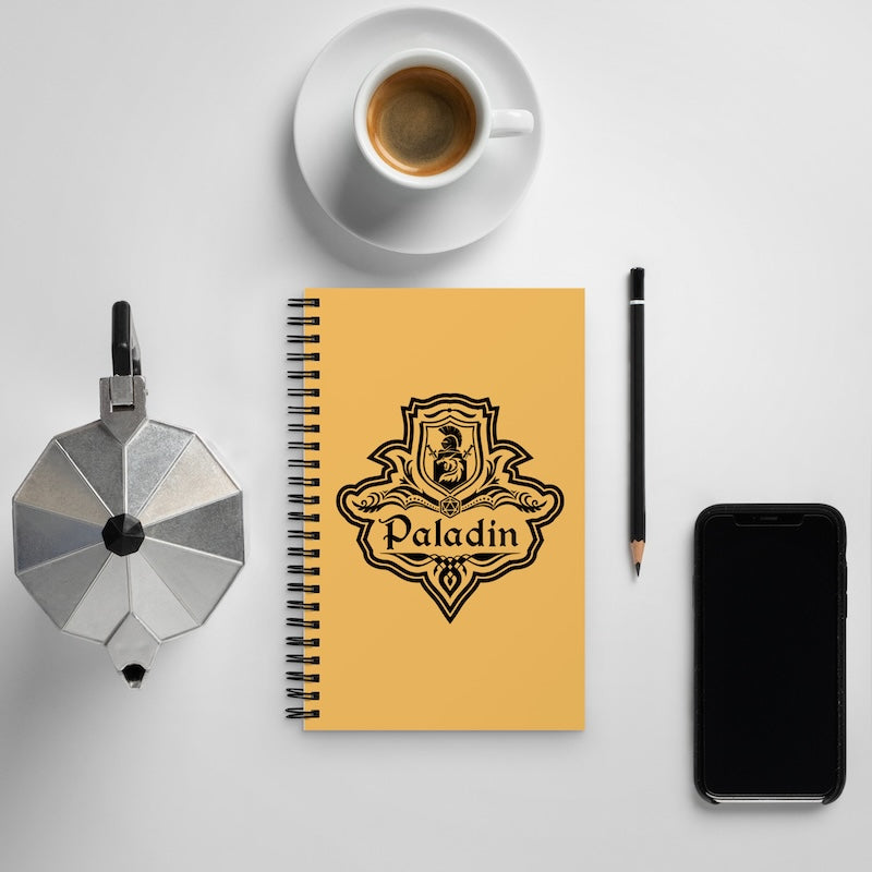 Yellow notebook with 'Paladin' logo, coffee cup, pen, and phone on a light gray background