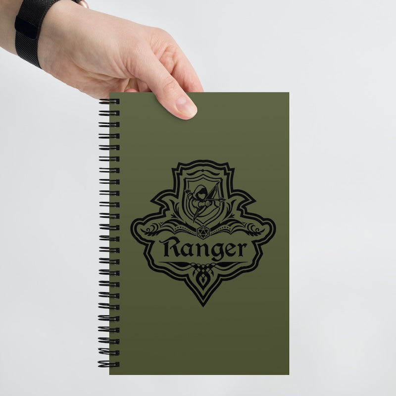 Green notebook with 'Ranger' emblem held by a hand on a light gray background