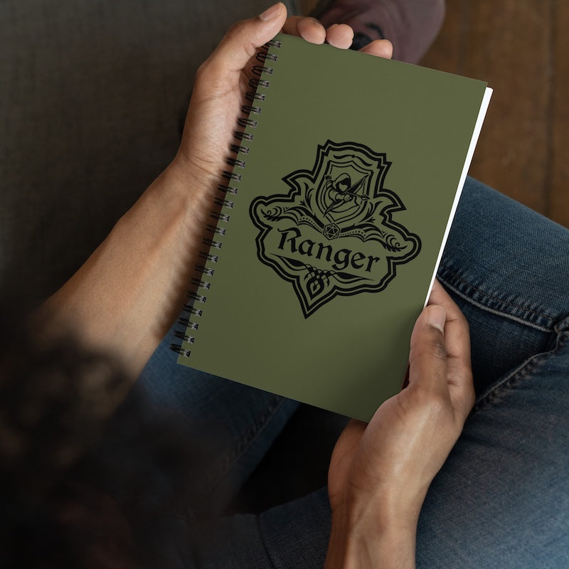 Person holding a green notebook with 'Ranger' emblem design.