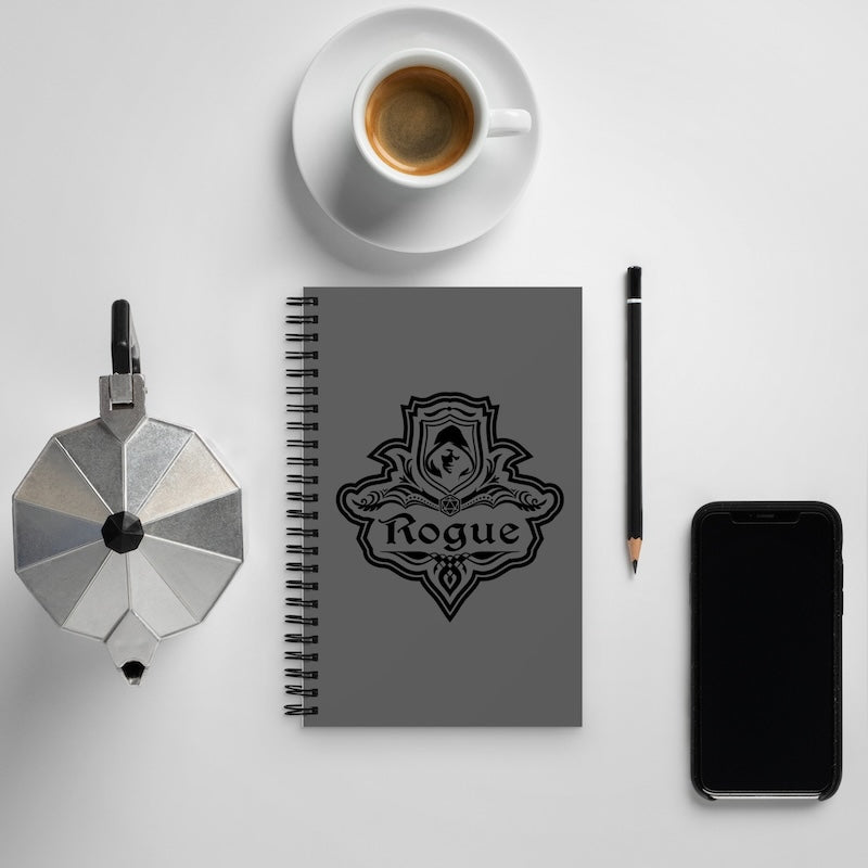 Gray notebook with 'Rogue' logo, coffee cup, pen, and phone on a light gray background