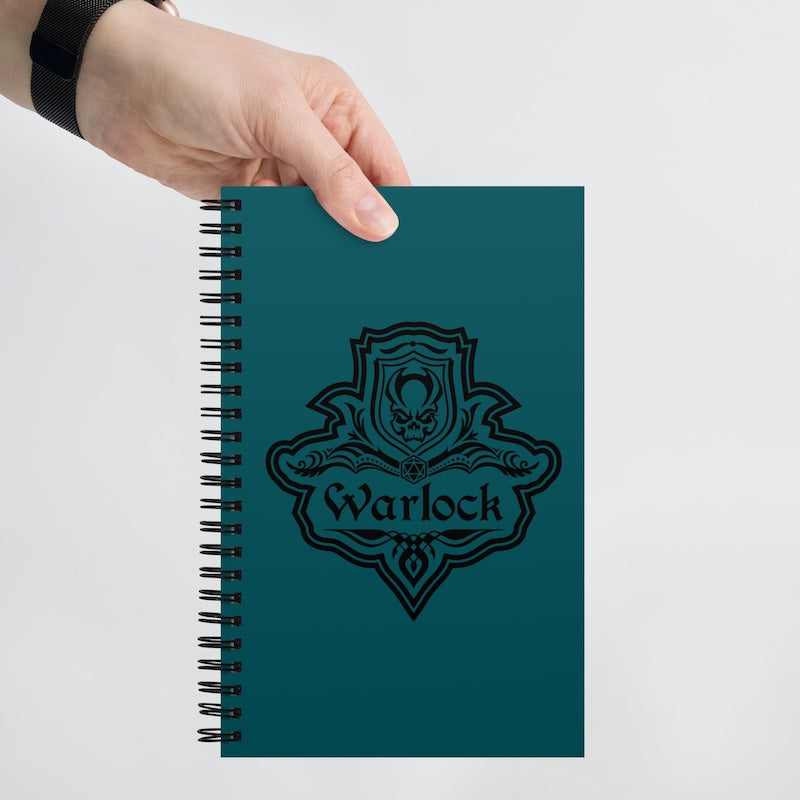 Teal notebook with 'Warlock' design held by a hand on a light gray background