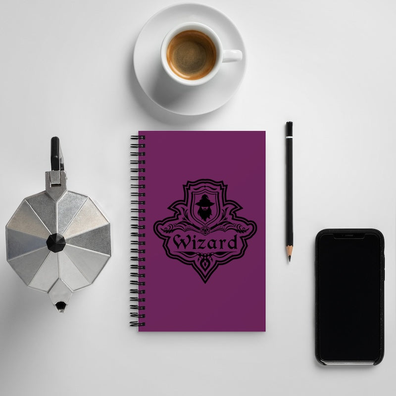 Purple notebook with 'Wizard' design, coffee cup, phone, and pencil on a white surface
