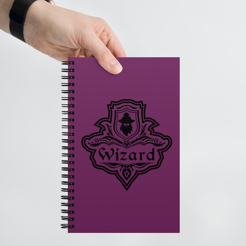Purple notebook with 'Wizard' design held by a hand on a light gray background