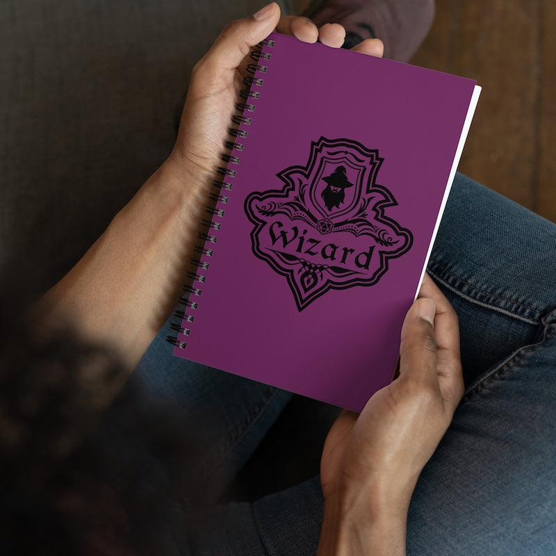 Purple notebook with 'Wizard' design held by a person wearing jeans.